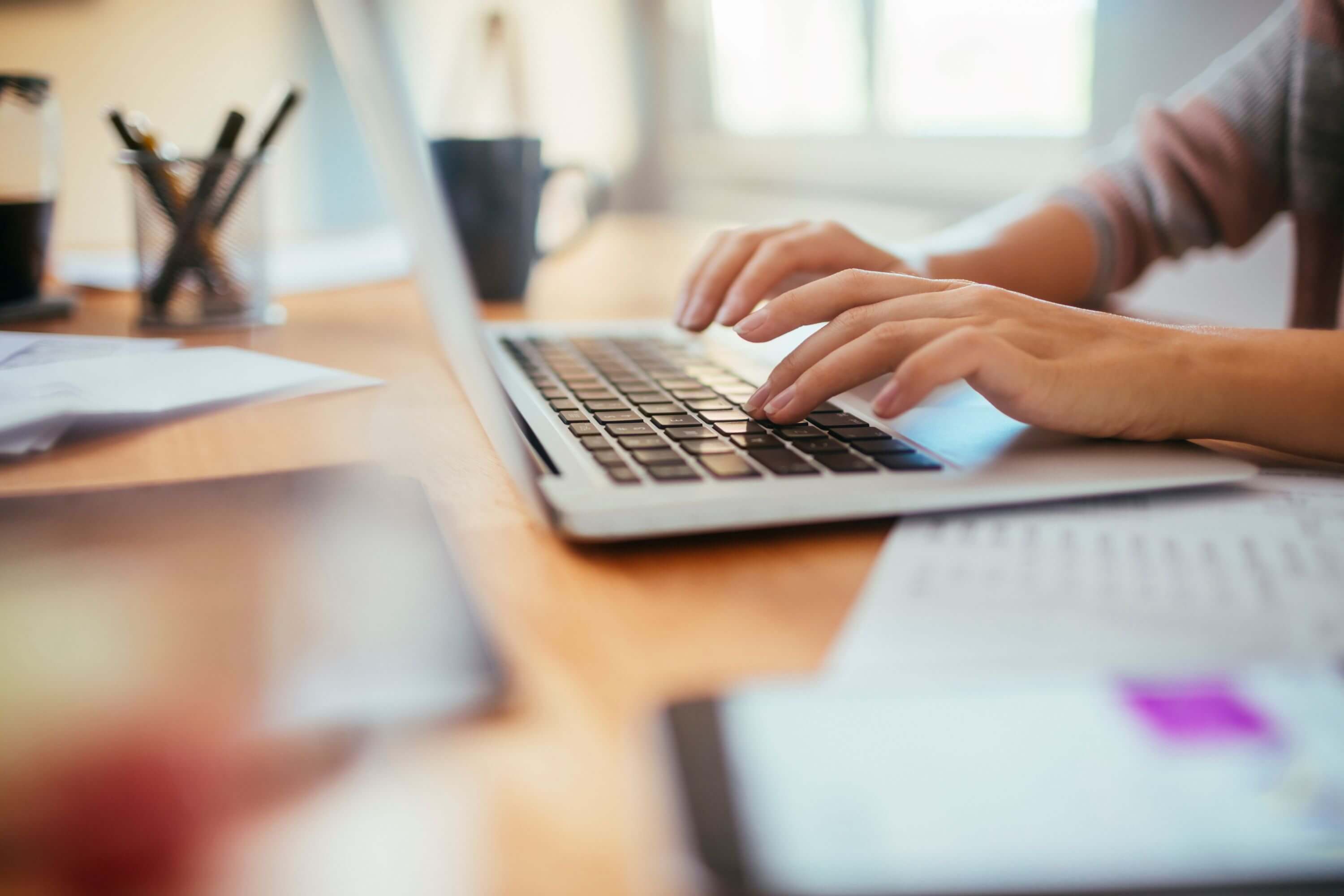 A person sitting at a desk, typing on a laptop